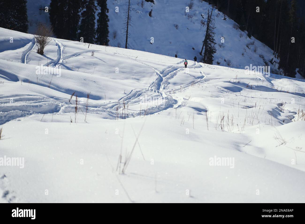 Un escursionista cammina lungo sentieri innevati in una valle di montagna. Foto Stock