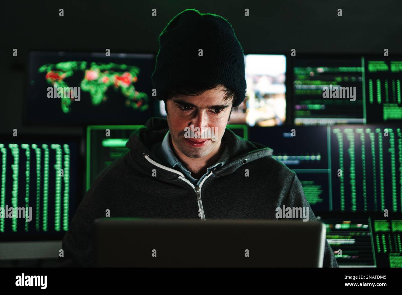 Hacker concentrato uomo, programmatore o sviluppatore digitando codice software su un computer portatile in background un sacco di schermi con testo. Concetto di sicurezza informatica. Foto di alta qualità Foto Stock