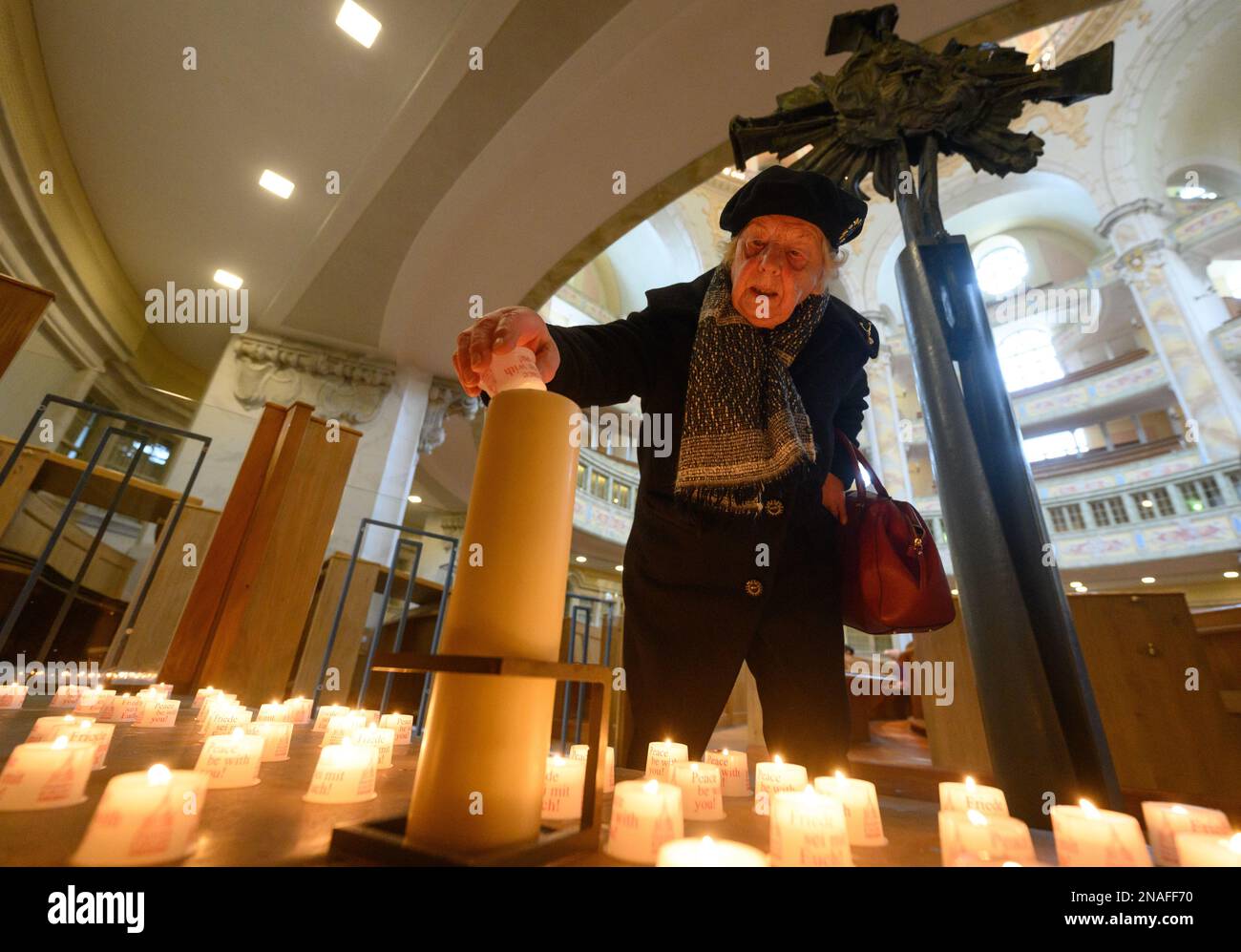 Dresda, Germania. 13th Feb, 2023. Karla Lorenz, 88 anni di Dresda residente e sopravvissuto ai bombardamenti del 1945, accende una cosiddetta luce della Pace sotto la croce torre distrutta della Frauenkirche nel 78th° anniversario della distruzione di Dresda nella seconda guerra mondiale Il 13 febbraio, la capitale dello stato di Dresda commemora la distruzione della città nella seconda guerra mondiale 78 anni fa. Il 13 e 14 febbraio 1945, i bombardieri alleati riducevano il centro della città sull'Elba a macerie. Fino a 25.000 persone hanno perso la vita. Credit: Robert Michael/dpa/Alamy Live News Foto Stock