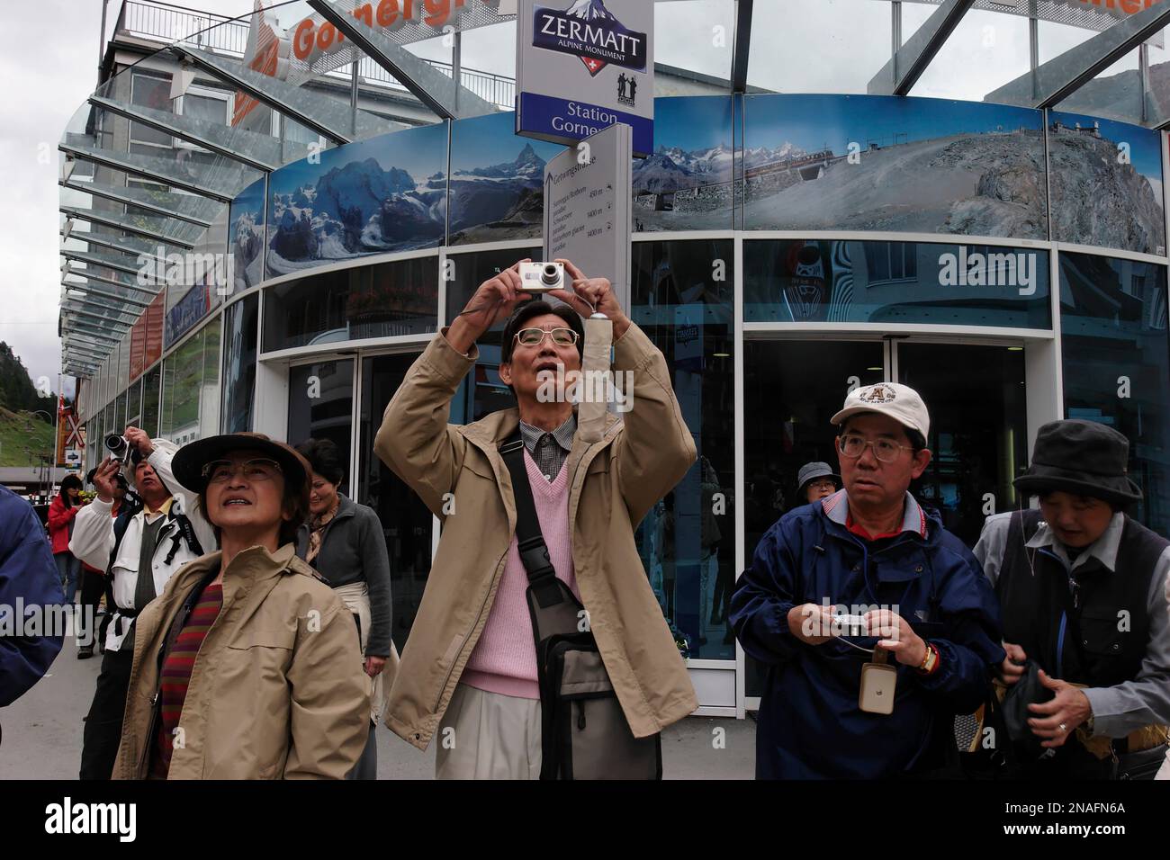 I turisti giapponesi si riuniscono e scattano foto dalla piazza principale di Zermatt, dove possono vedere il famoso picco piramidale quasi simmetrico, la questione... Foto Stock