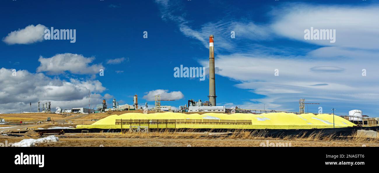 Impianto a gas e pila di zolfo giallo brillante con cielo blu e nuvole, a sud di Pincher Creek; Alberta, Canada Foto Stock