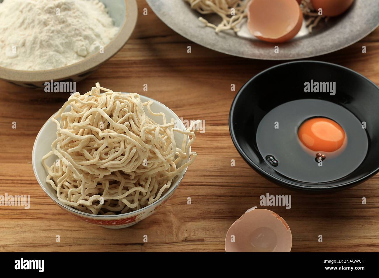 Noodle di uovo asiatico essiccato su tavola di legno, cottura che fa processo Foto Stock