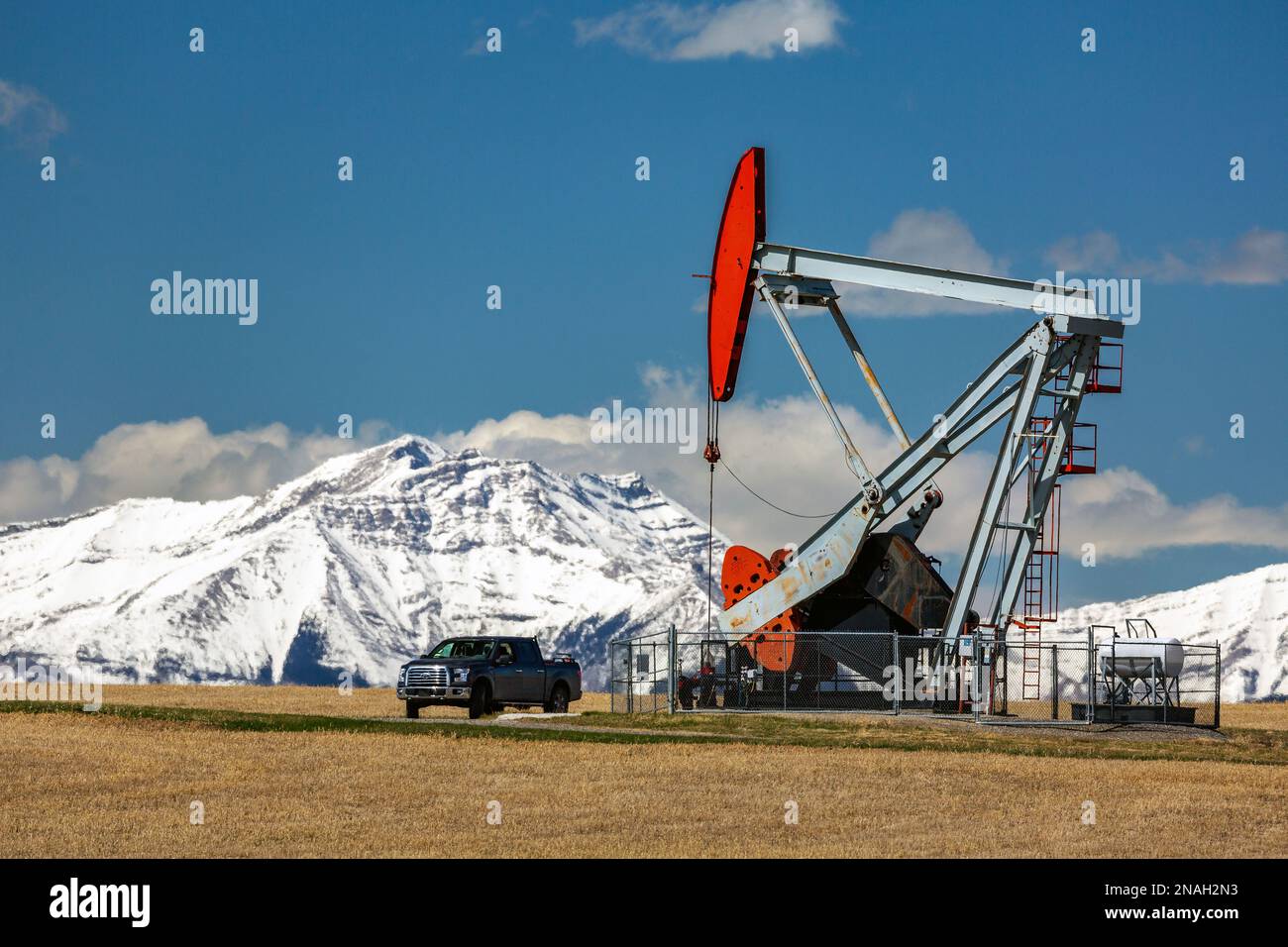 Grande zucca con camion e catena montuosa innevata e cielo blu sullo sfondo, a nord di Longview, Alberta; Alberta, Canada Foto Stock