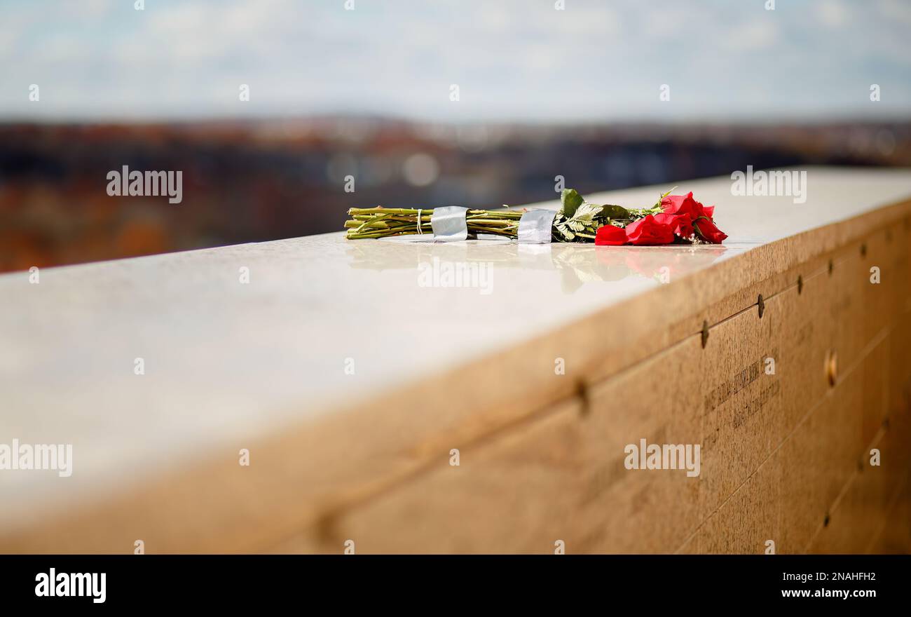 Mazzo di rose rosse poste su pareti in pietra di marmo presso la tomba commemorativa del mausoleo Foto Stock