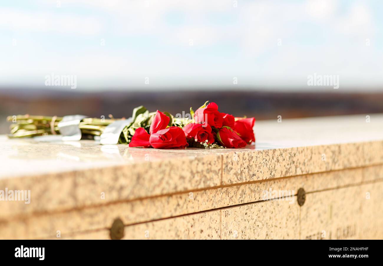 Mazzo di rose rosse poste su pareti in pietra di marmo presso la tomba commemorativa del mausoleo Foto Stock