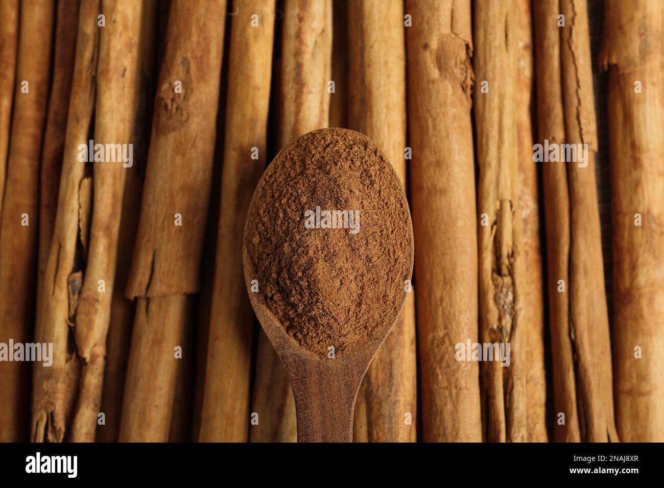 Cucchiaio di legno con cannella aromatica in polvere su bastoncini, vista dall'alto Foto Stock