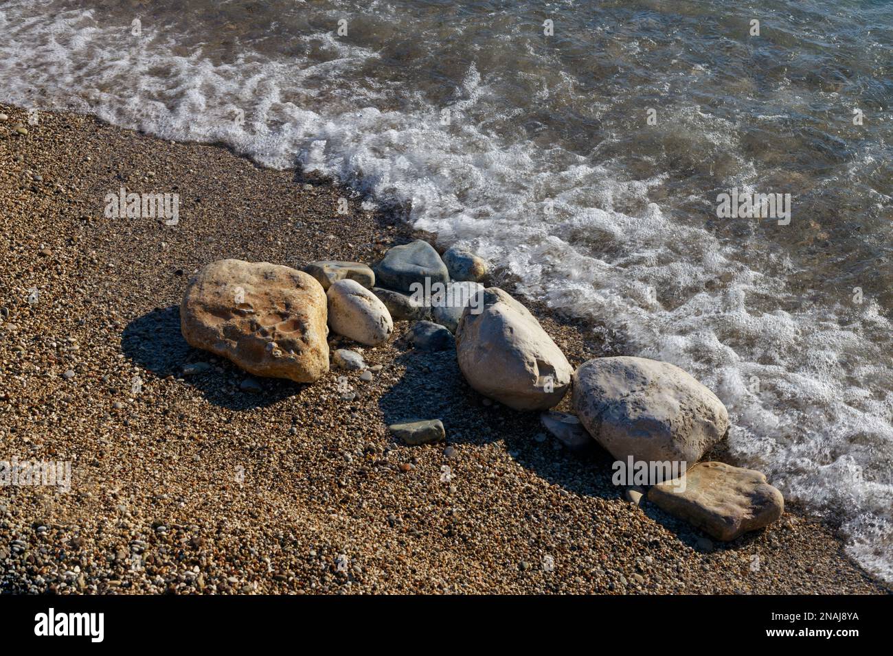Sezione di spiaggia di mare con alcune pietre più grandi. Foto Stock