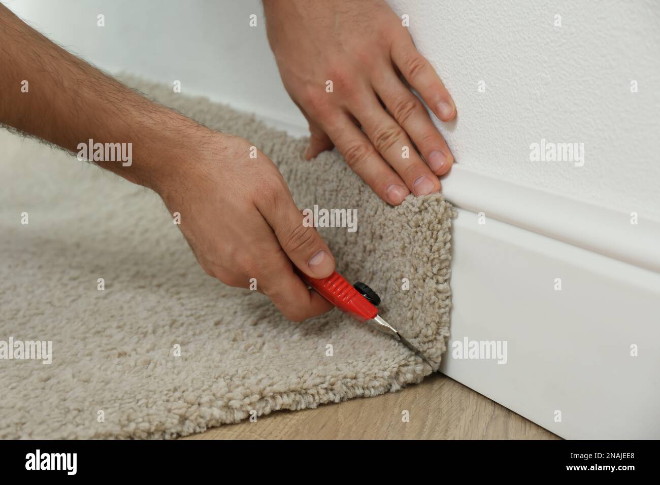 Uomo che taglia la nuova moquette pavimento in interni, primo piano. Spazio  per il testo Foto stock - Alamy