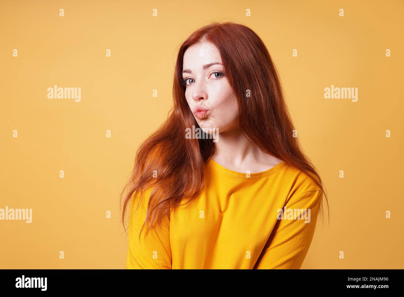 una giovane donna sciocca che le pukering le labbra per un bacio o anatra espressione facciale Foto Stock