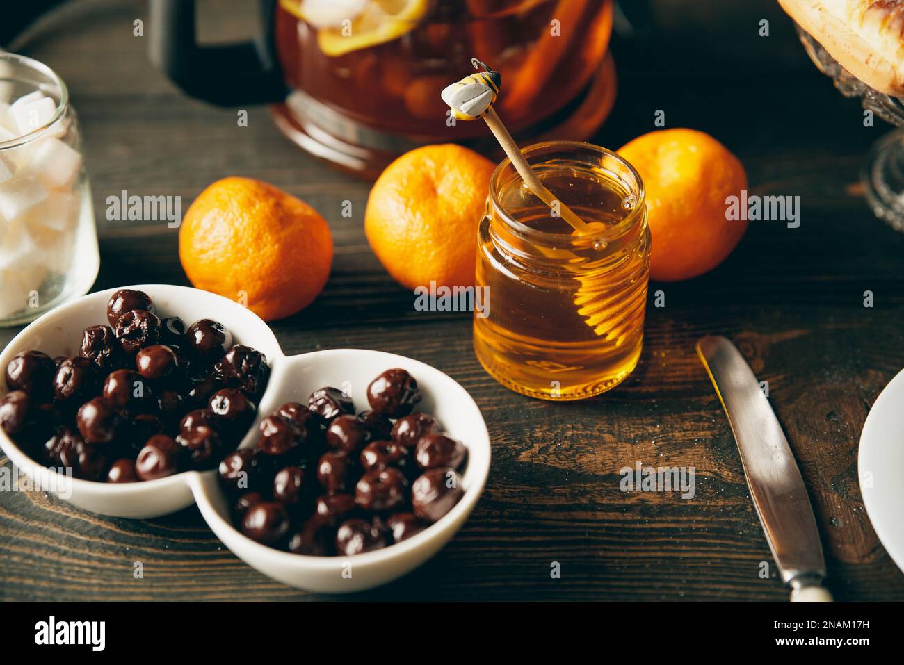 Miele in vaso di vetro con cucchiaia di miele di legno su un tavolo servito. Concetto di ingredienti naturali biologici, stile rustico Foto Stock