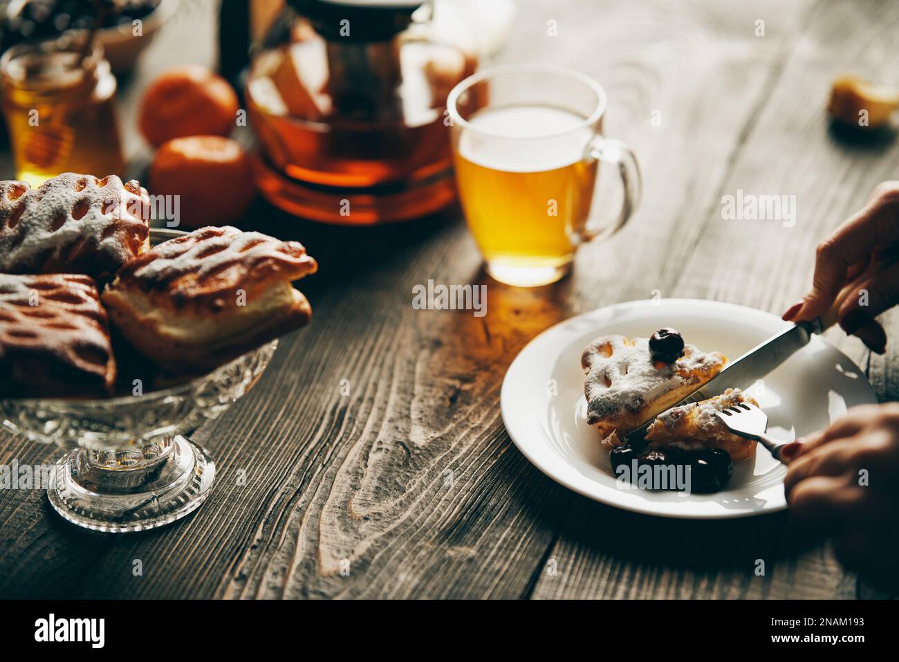 Immagine ravvicinata di una donna che mangia dolci alla ciliegia con forchetta e maglia nel bar. Sfondo panetteria, concetto di cibo Foto Stock