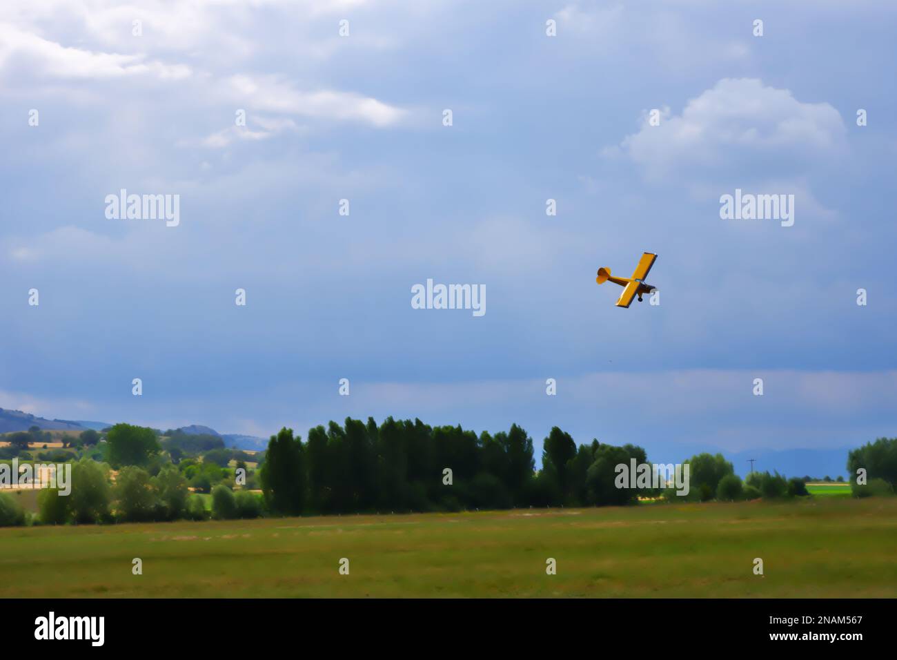 Velivolo giallo a motore singolo che si manovra vicino al terreno con cielo nuvoloso sullo sfondo Foto Stock