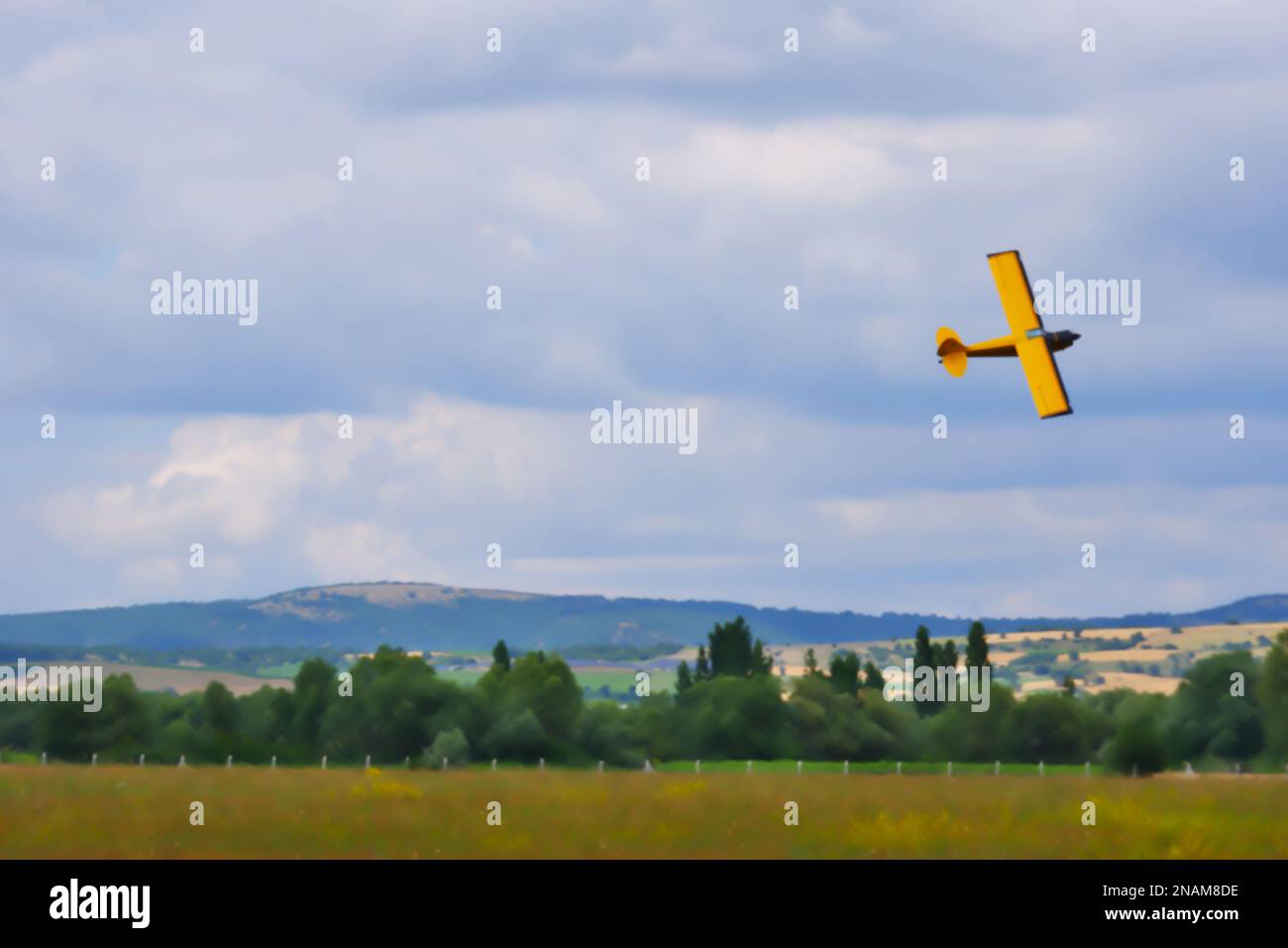 Velivolo giallo a motore singolo che si manovra vicino al terreno con cielo nuvoloso sullo sfondo Foto Stock