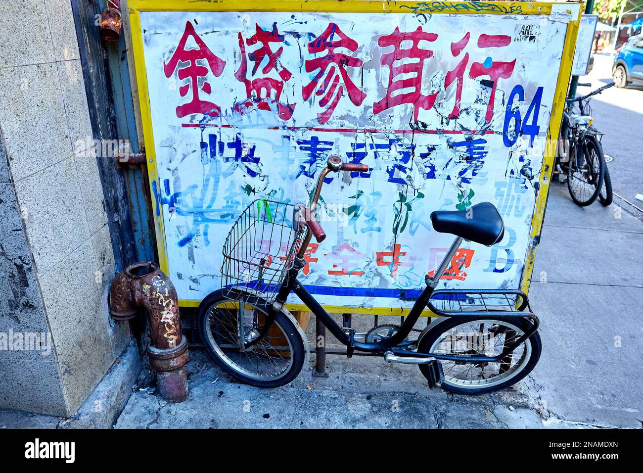 Bicicletta con cestino accanto al tubo dell'acqua sul marciapiede a Chinatown, New York Foto Stock