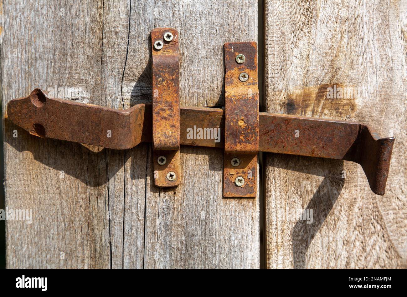 Vecchio bullone di bloccaggio in ferro arrugginito alla porta del fienile in legno Foto Stock