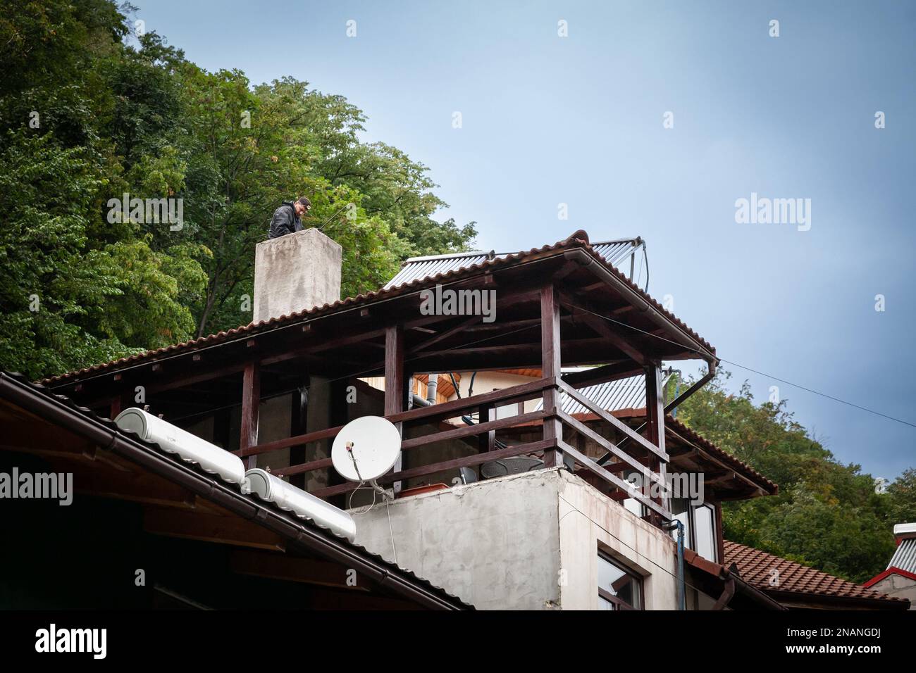 Immagine di una spazzatrice a camino, una spazzatura, lavorando per pulire il camino di una casa rumena in Baile Herculane. Foto Stock