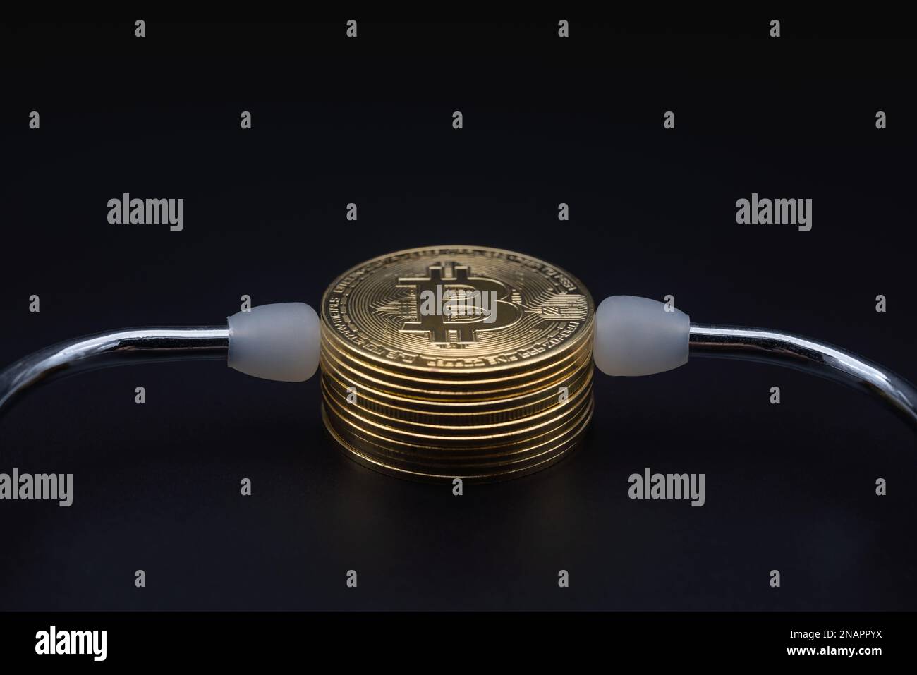 Business , denaro, tecnologia e criptovaluta. Primo piano di monete d'oro bitcoin con stetoscopio medico su sfondo nero. Foto Stock