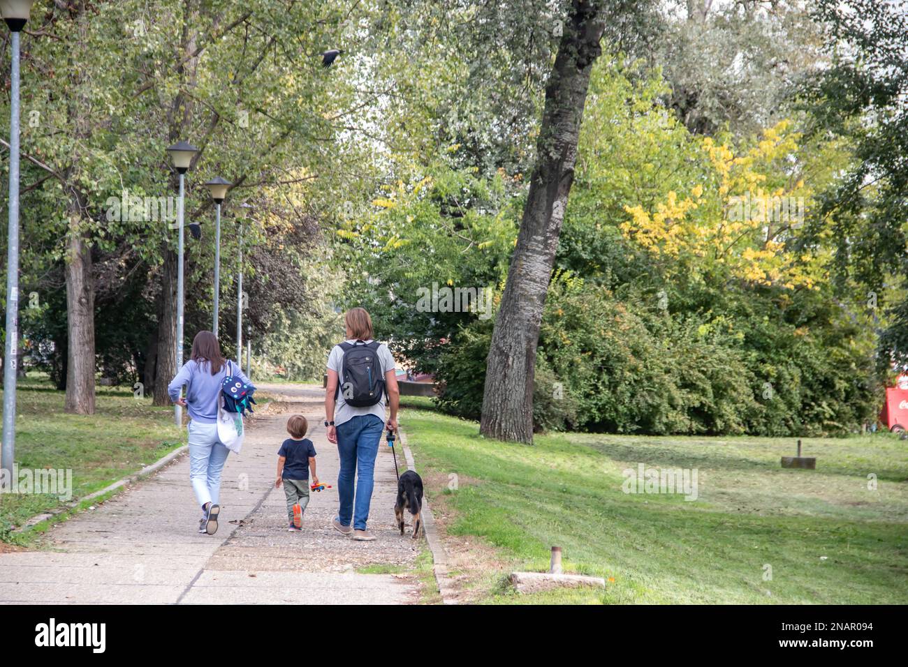La famiglia con i bambini si diverti a passeggiare nel parco durante il giorno soleggiato del fine settimana Foto Stock