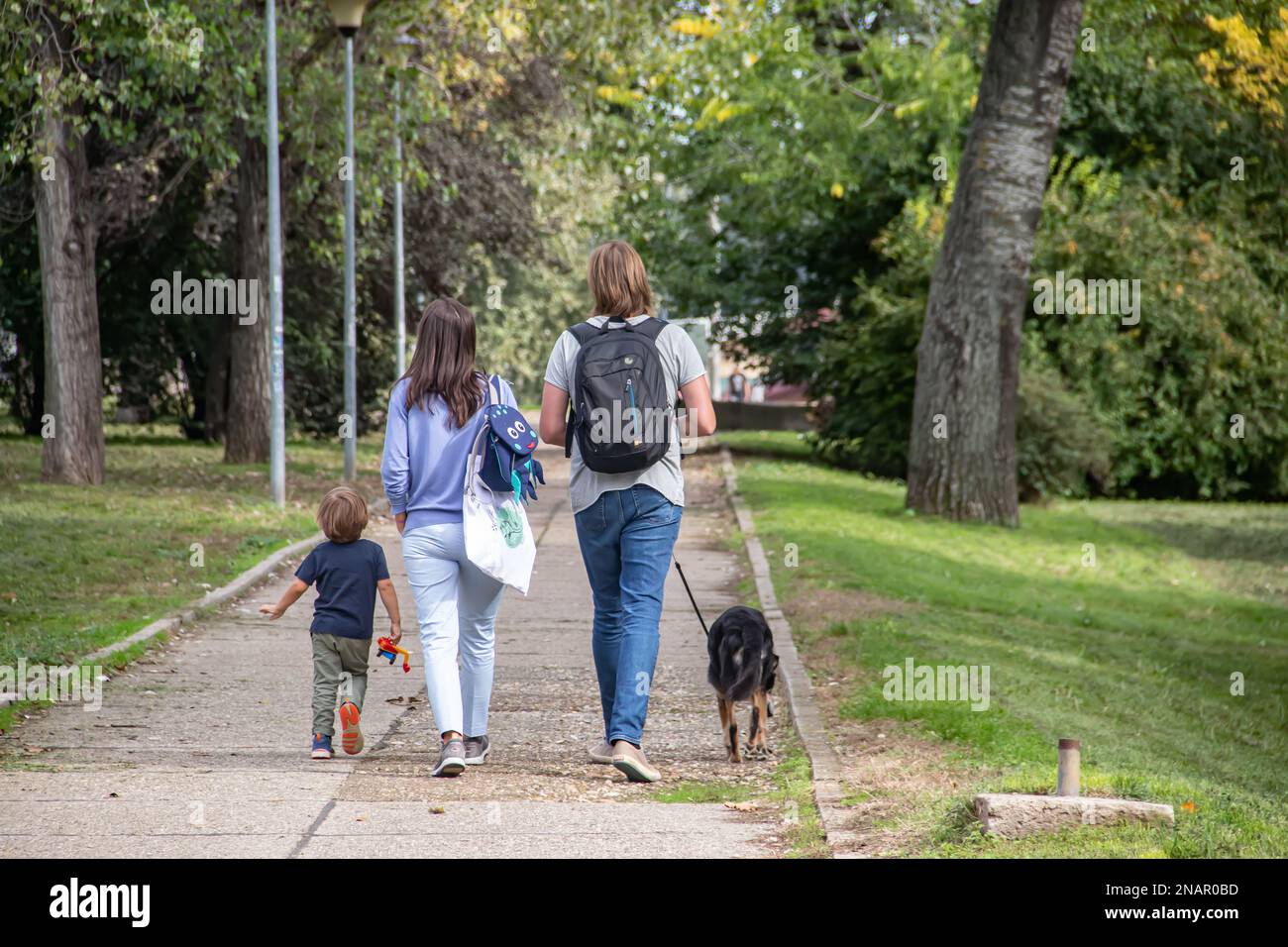 La famiglia con i bambini si diverti a passeggiare nel parco durante il giorno soleggiato del fine settimana Foto Stock