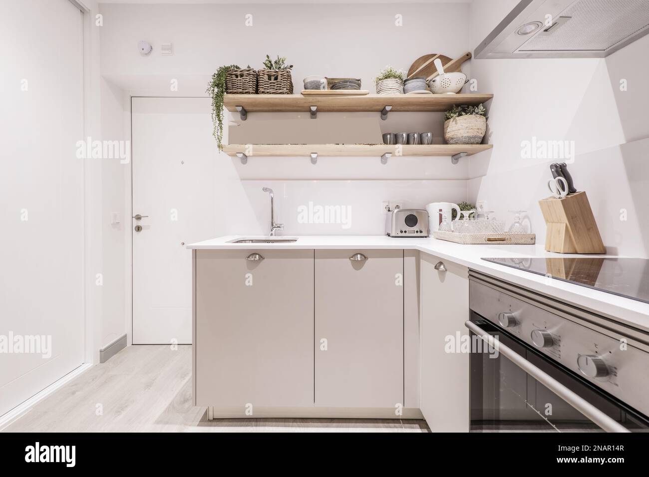 Appartamento vacanza cucina con base grigia con manici a ciotola in acciaio inox, ripiani in legno e piccoli elettrodomestici su un piano bianco Foto Stock