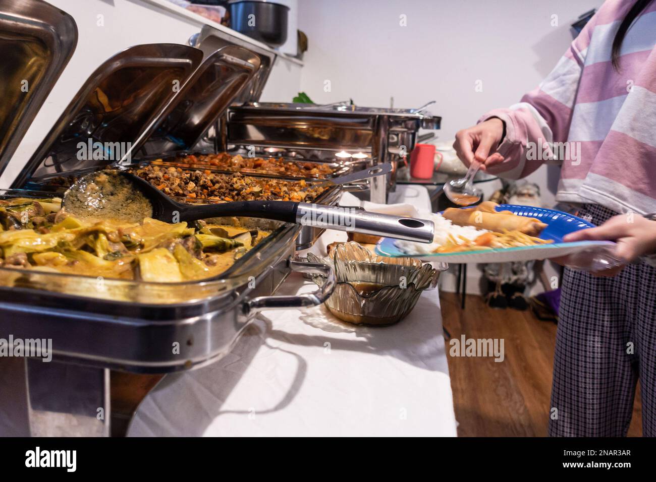 Una selezione a buffet di piatti filippini in piatti di sfregamento in acciaio inossidabile durante una festa Foto Stock