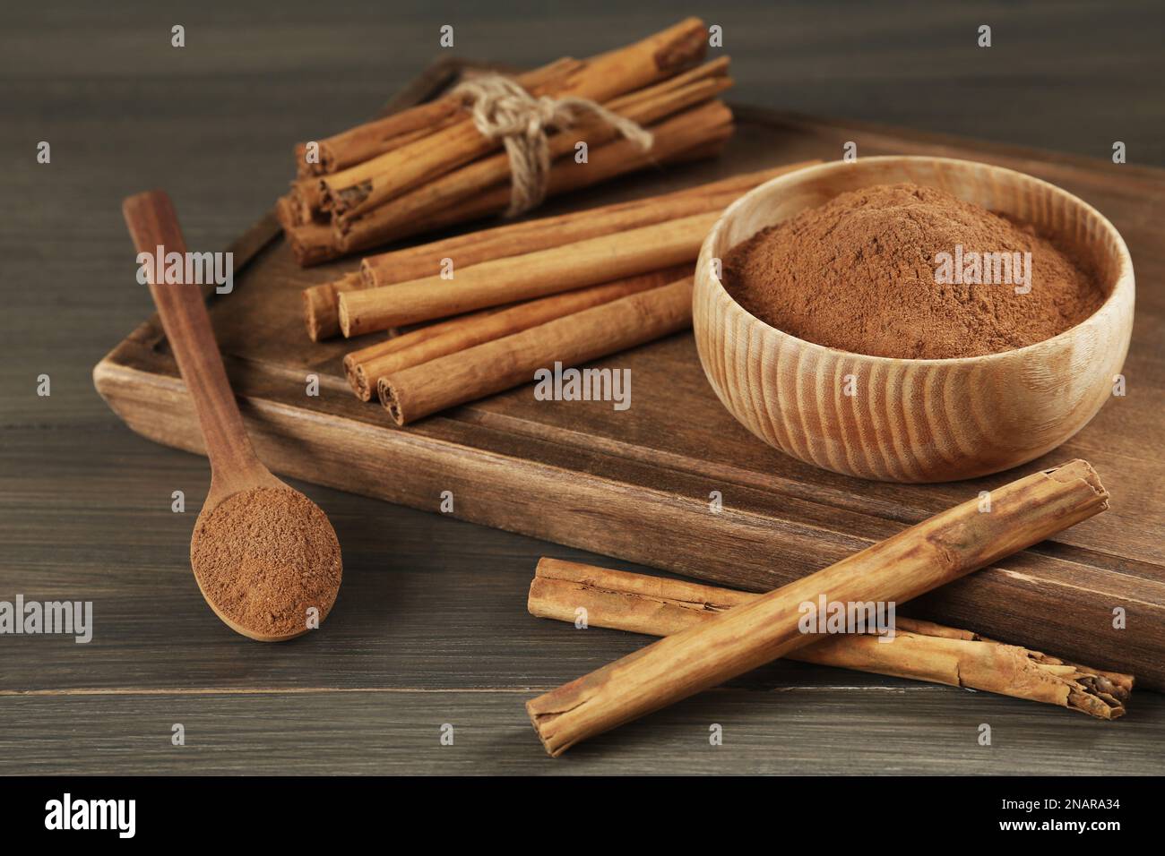 Aromatica bastoncini di cannella e polvere sul tavolo di legno Foto Stock