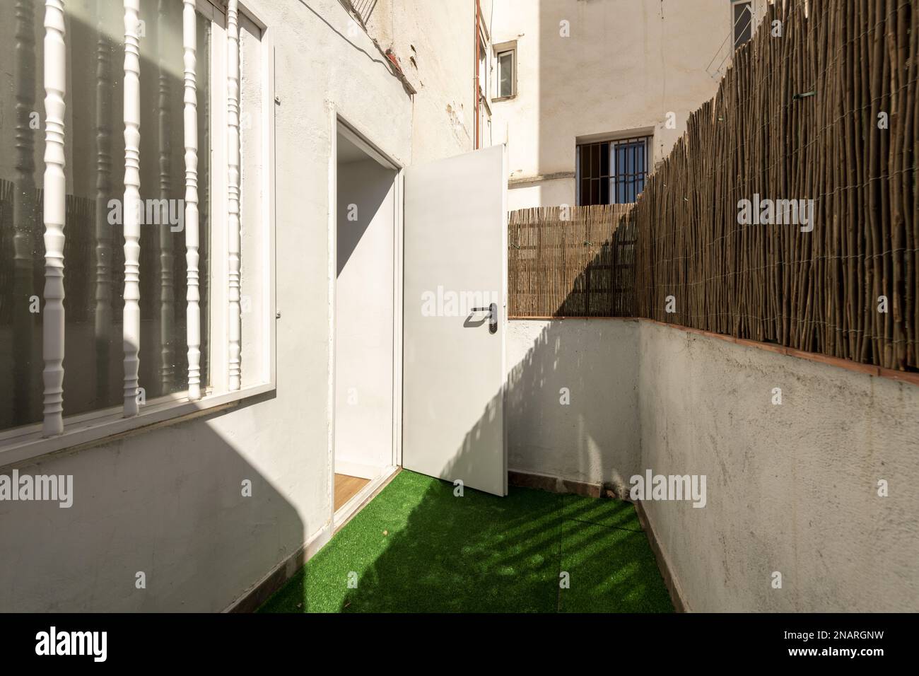 Piccola terrazza di una casa al piano terra con erba artificiale e canne da nascondere dalla vista Foto Stock