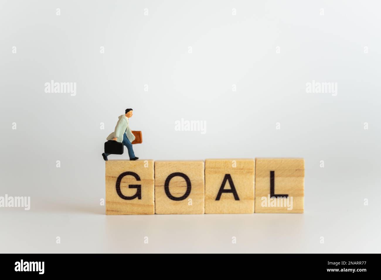 Concetto di viaggio e di affari. Uomini d'affari miniatura figura persone con borsa valigia a piedi sul blocco di lettere di legno wording obiettivo. Foto Stock