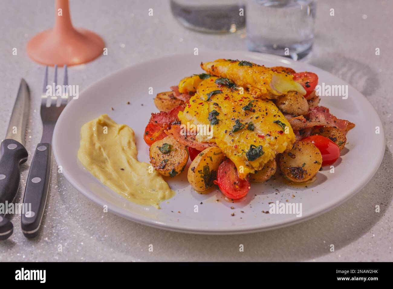 Filetto di eglefino con patate e verdure guarnite con erbe aromatiche e salsa di pesce. Foto Stock