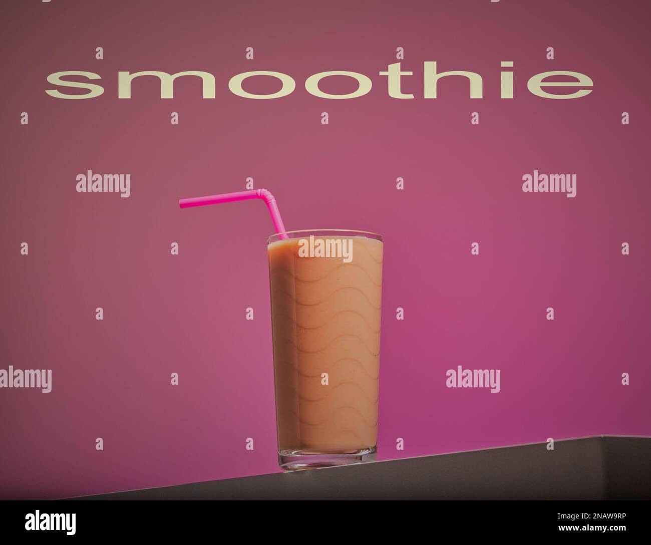 Frullato rinfrescante con una cannuccia rosa su sfondo rosa sfumato. Foto Stock