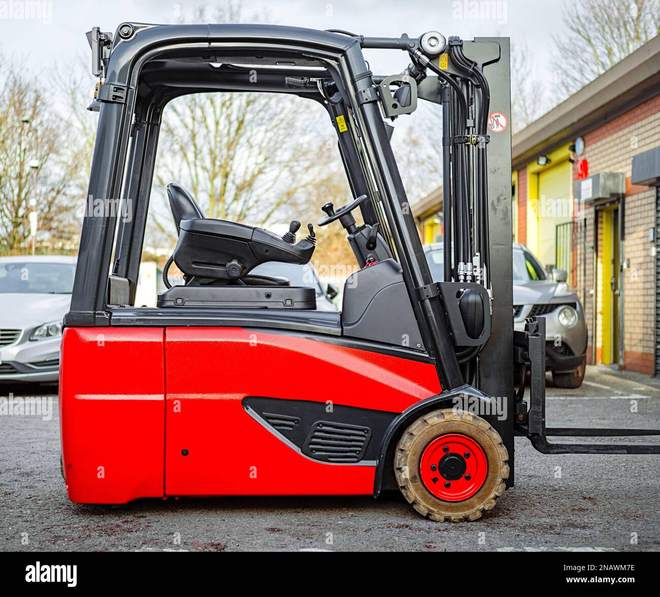 Carrello elevatore a forche elettrico alimentato a batteria seduto nel magazzino cantiere colore rosso controbilancia veicolo Foto Stock