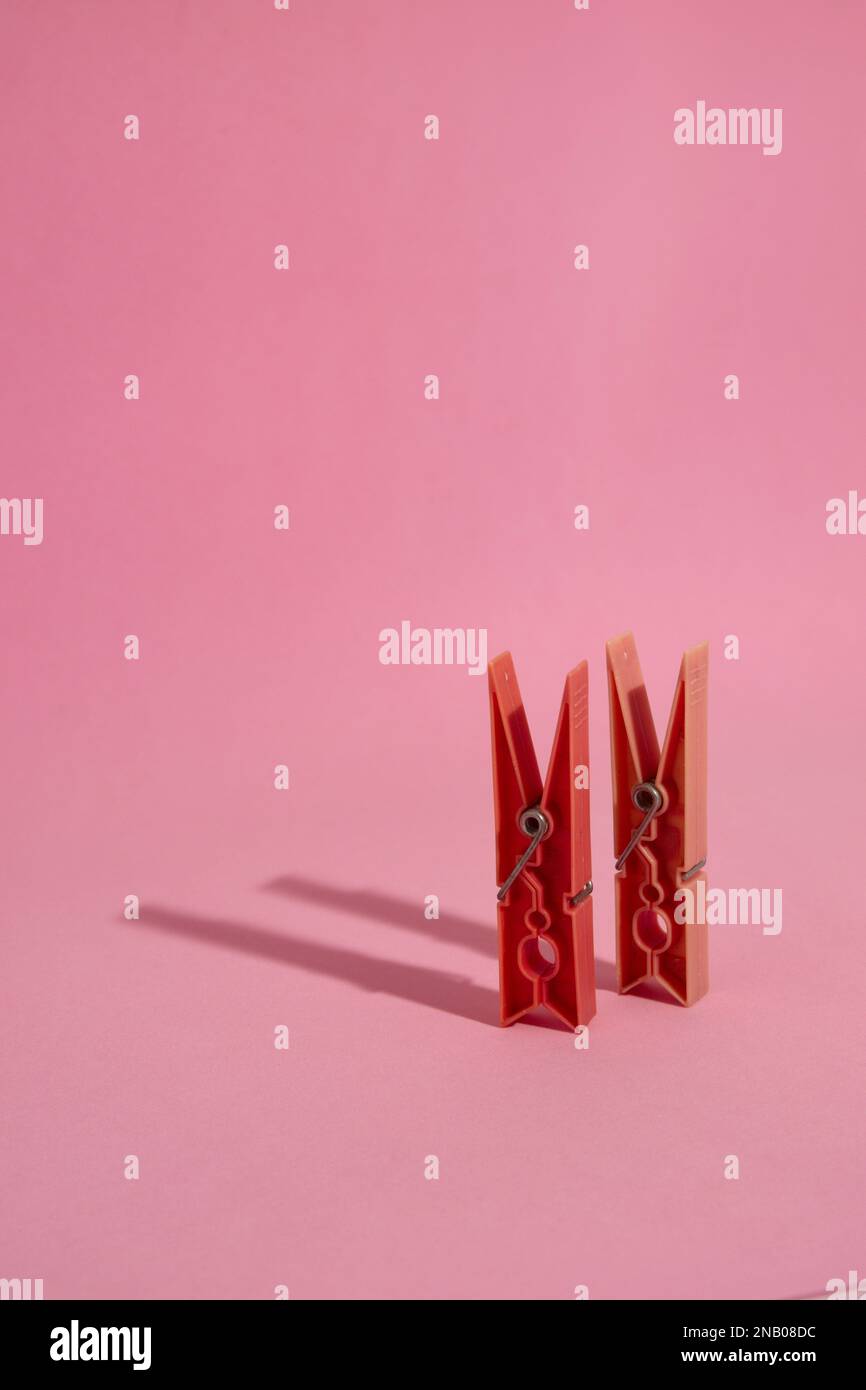 Primo piano di due clothespins rossi isolati e in piedi su sfondo rosa con spazio copia, in parte occupato dall'ombra di getto dei pioli Foto Stock Primo piano di due clothespins rossi isolati e in piedi su sfondo rosa con spazio copia, in parte occupato dall'ombra di getto dei pioli Foto Stock