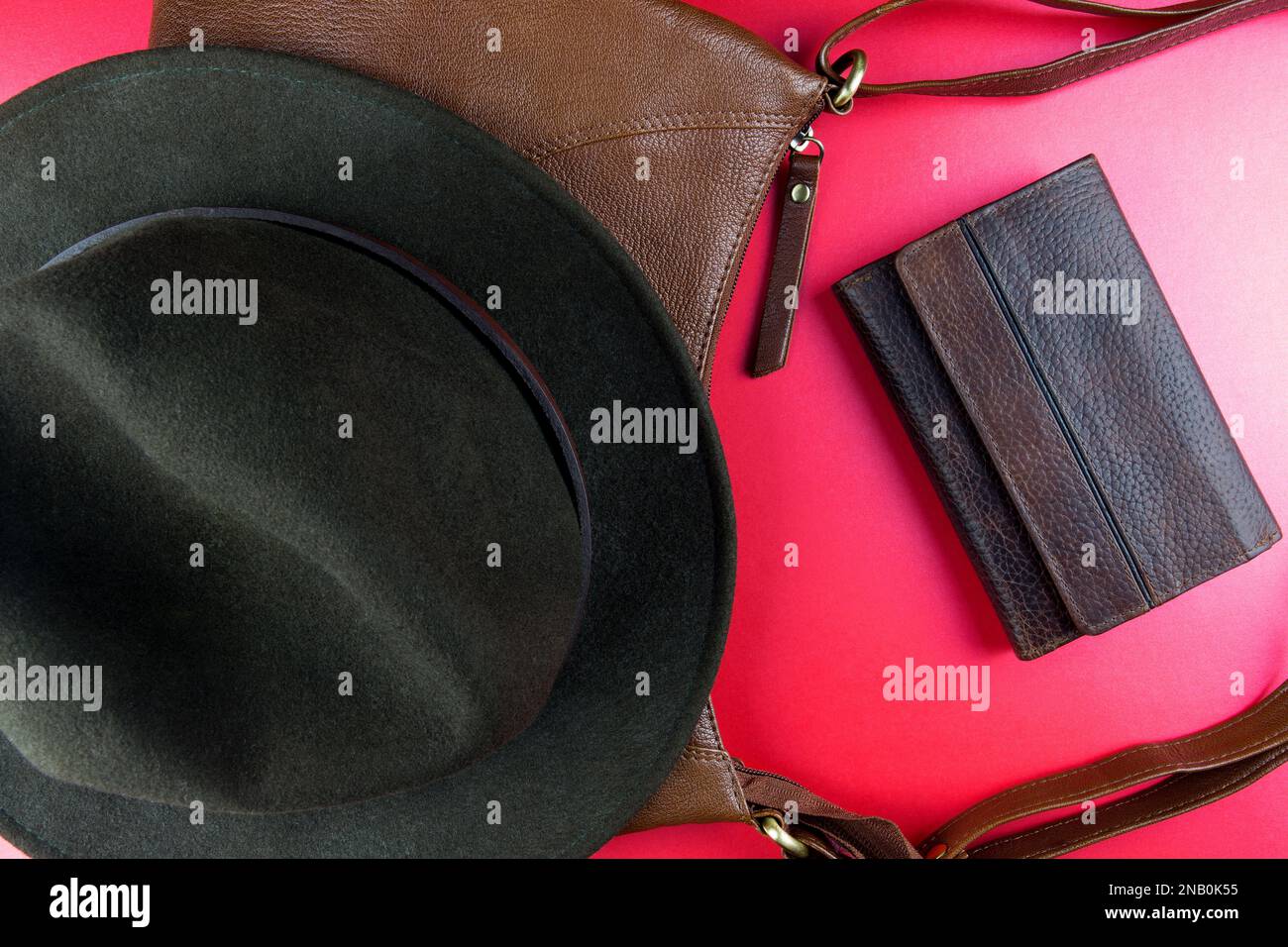 Borsa in pelle con cappello in feltro e portafoglio in pelle su un top da tavolo rosso Foto Stock