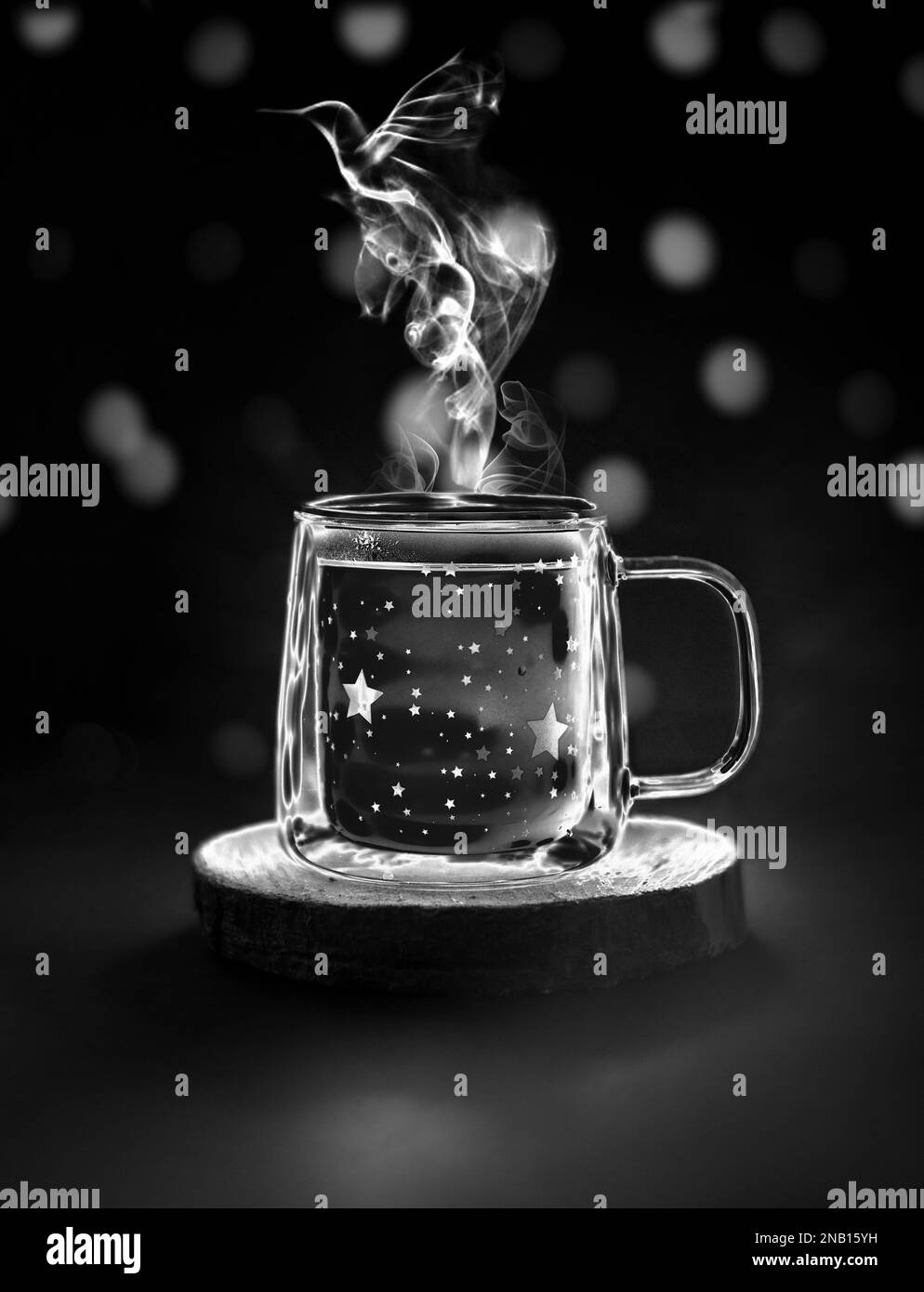 Vita morta magica. Foto in bianco e nero di una semplice tazza con vapore a forma di colibrì e bel bokeh sullo sfondo. Foto Stock