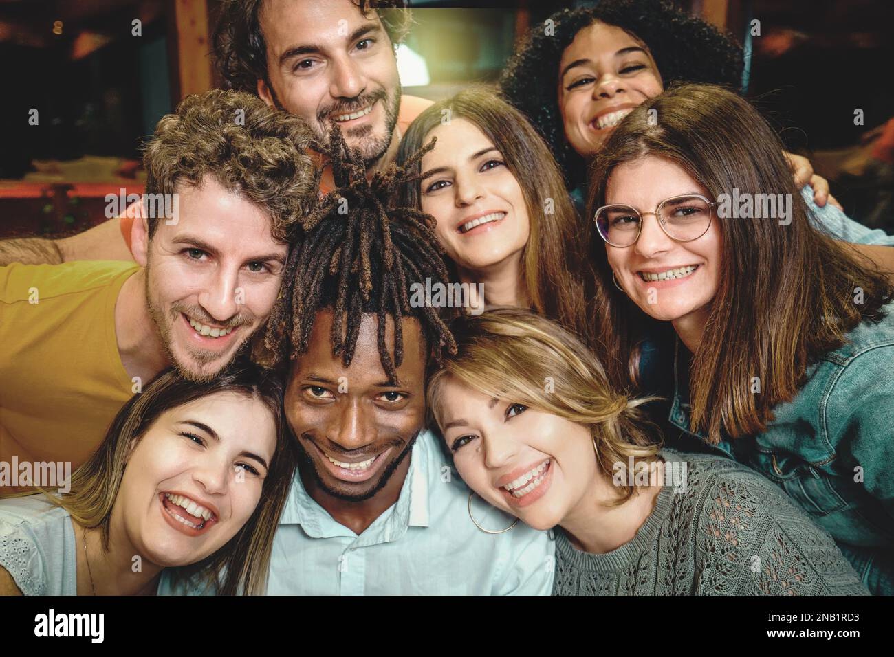 Un'immagine che mostra un ritratto da vicino di 8 giovani multiculturali sorridenti e felici mentre si riuniscono la testa per una foto di gruppo. Foto Stock