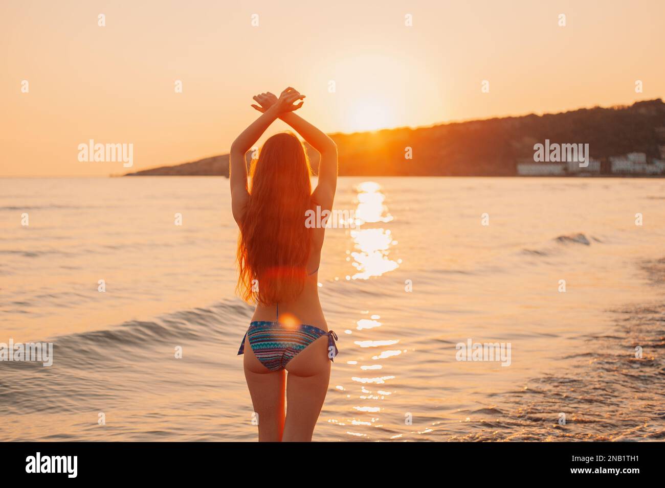 Silhouette felice bella giovane donna un lungo capello in un costume da bagno in piedi braccia stese sulla spiaggia al Tramonto Mare Adriatico, in Montenegro Foto Stock