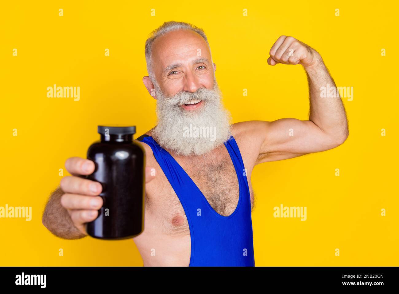 Foto della persona anziana sportiva mostra spazio vuoto braccio bottiglia flexing bicipite isolato su sfondo giallo Foto Stock