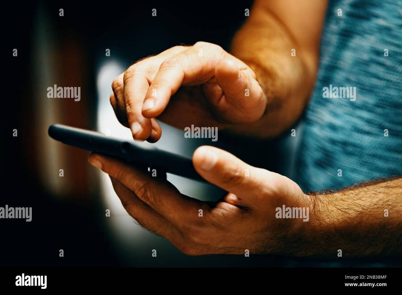 Invio di sms e condivisione di contenuti sui social network dall'interno della casa.immagine ravvicinata della mano dell'uomo che tiene il suo smartphone. Foto Stock