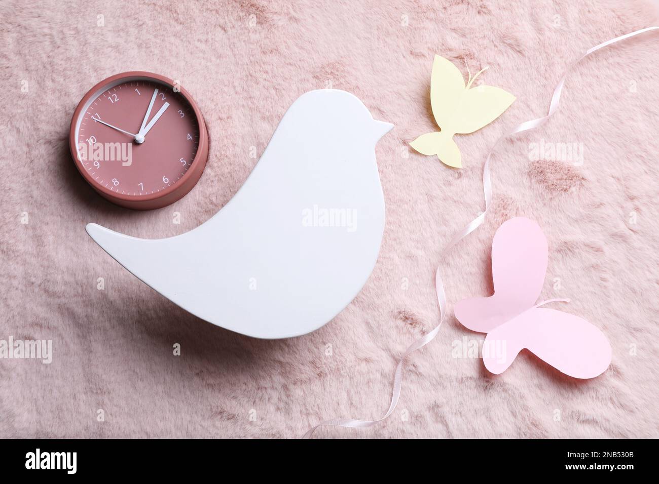 Composizione piatta con lampada da notte per bambini a forma di uccello su tessuto rosa Foto Stock