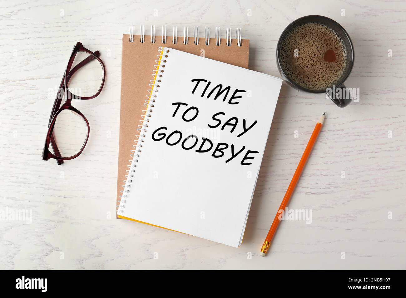 Notebook con testo Time to Say Arrivederci, cancelleria da ufficio e tazza di caffè su tavolo di legno bianco, piatto Foto Stock