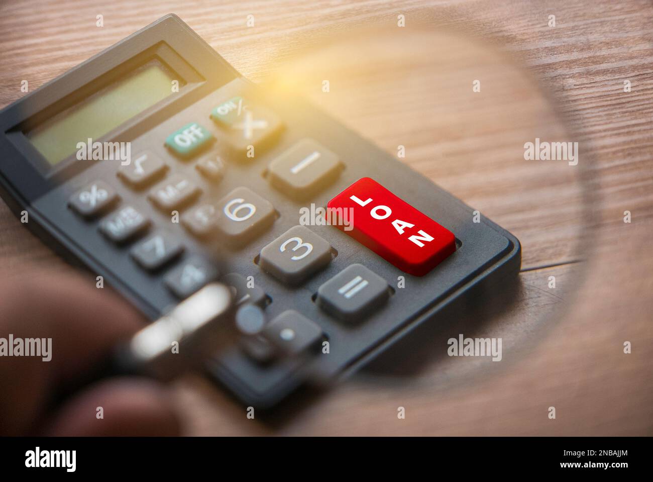 Fuoco selettivo della mano che tiene la lente d'ingrandimento che mette a fuoco su un tasto rosso del PRESTITO. Concetto di business e finanza. Foto Stock