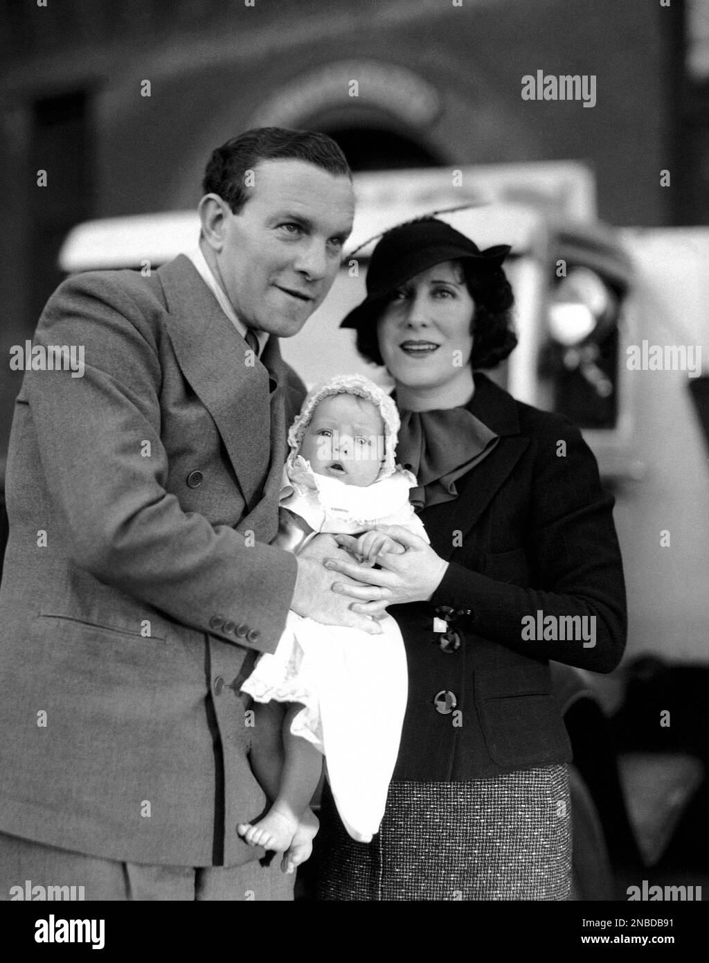 Sandra Jean Burns, four-month-old adopted daughter of George Burns and Gracie Allen, film comedians, poses with her new parents on her arrival in Hollywood, Dec. 3, 1934. (AP Photo) Foto Stock
