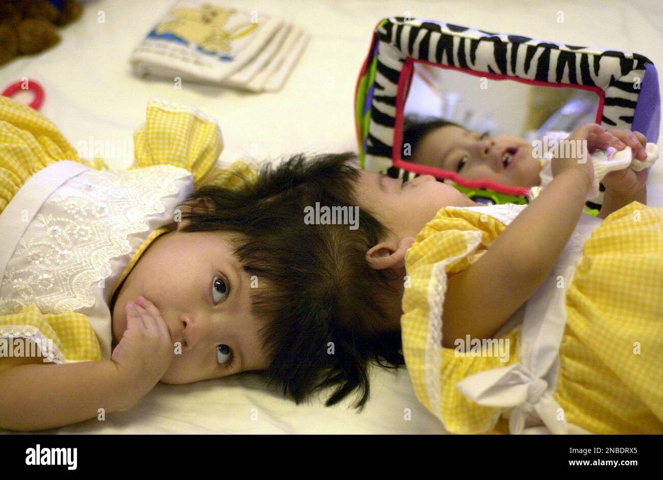 FILE - This June 22, 2002 file photo shows conjoined twins Maria Teresa Alvarez, left and Maria de Jesus Alvarez playing in their hospital bed at UCLA Medical center in Los Angeles. The twins, separated in a successful operation are scheduled to celebrate their 10th birthdays Aug. 6, 2011. (AP Photo/Krista Niles) Foto Stock