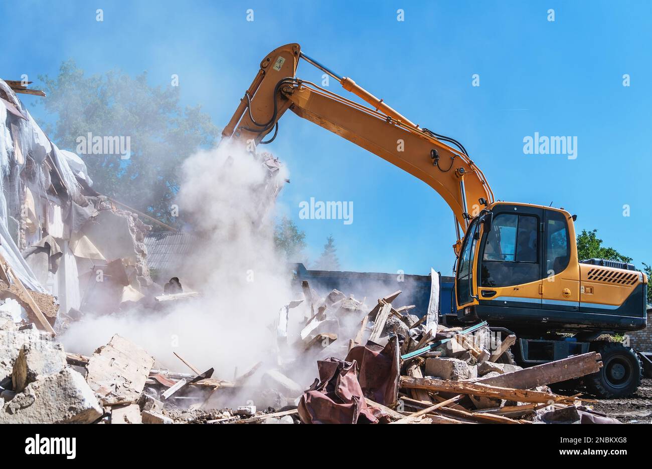 Demolizione di edifici. L'escavatore distrugge la vecchia casa. Foto Stock