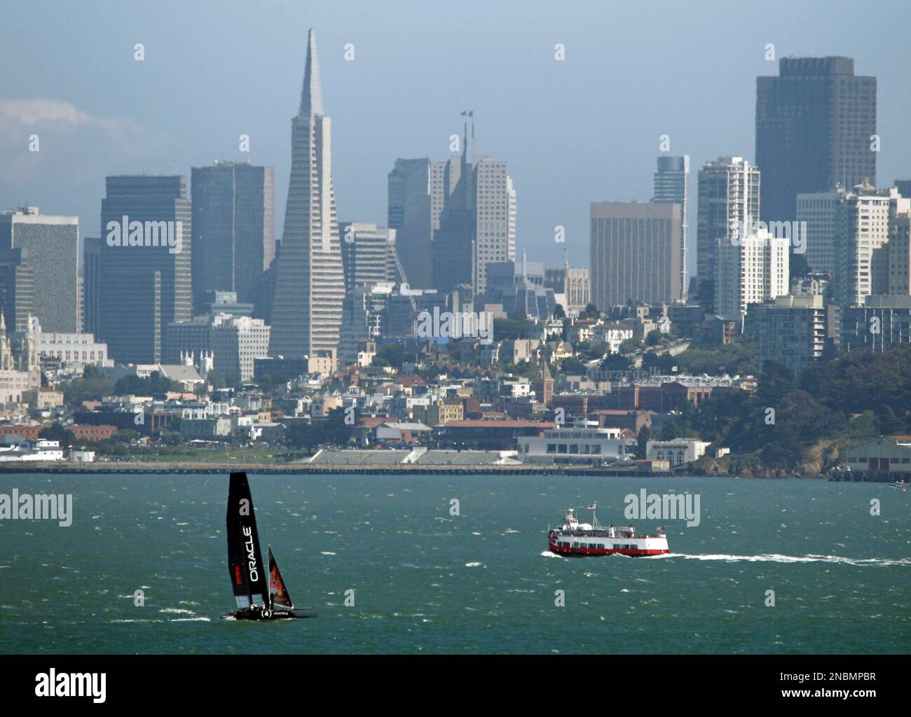 An Oracle Racing AC45, skippered by James Spithill, makes its way past a cruise boat and the San Francisco skyline in this view from Sausalito, Calif., Monday, June 13, 2011. The forerunner to the AC72--which teams will race in the Louis Vuitton Cup and America's Cup finals in 2013 in San Francisco--the AC45 will be featured at the AC World Series this year and next. (AP Photo/Eric Risberg) Foto Stock