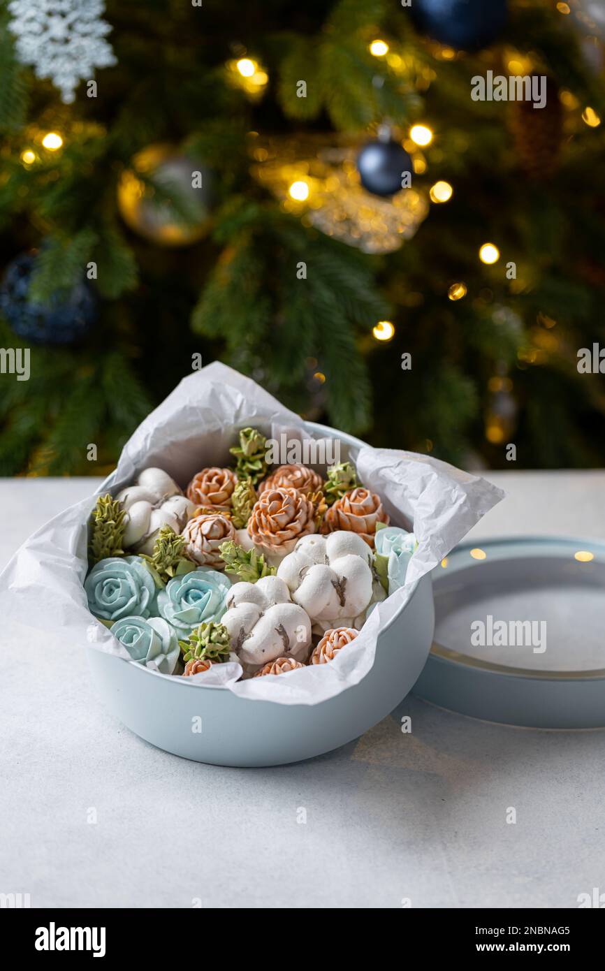 Mazzo di fiori marshmallow in una scatola regalo sullo sfondo di un albero di Natale, il concetto di un umore festivo. Foto Stock