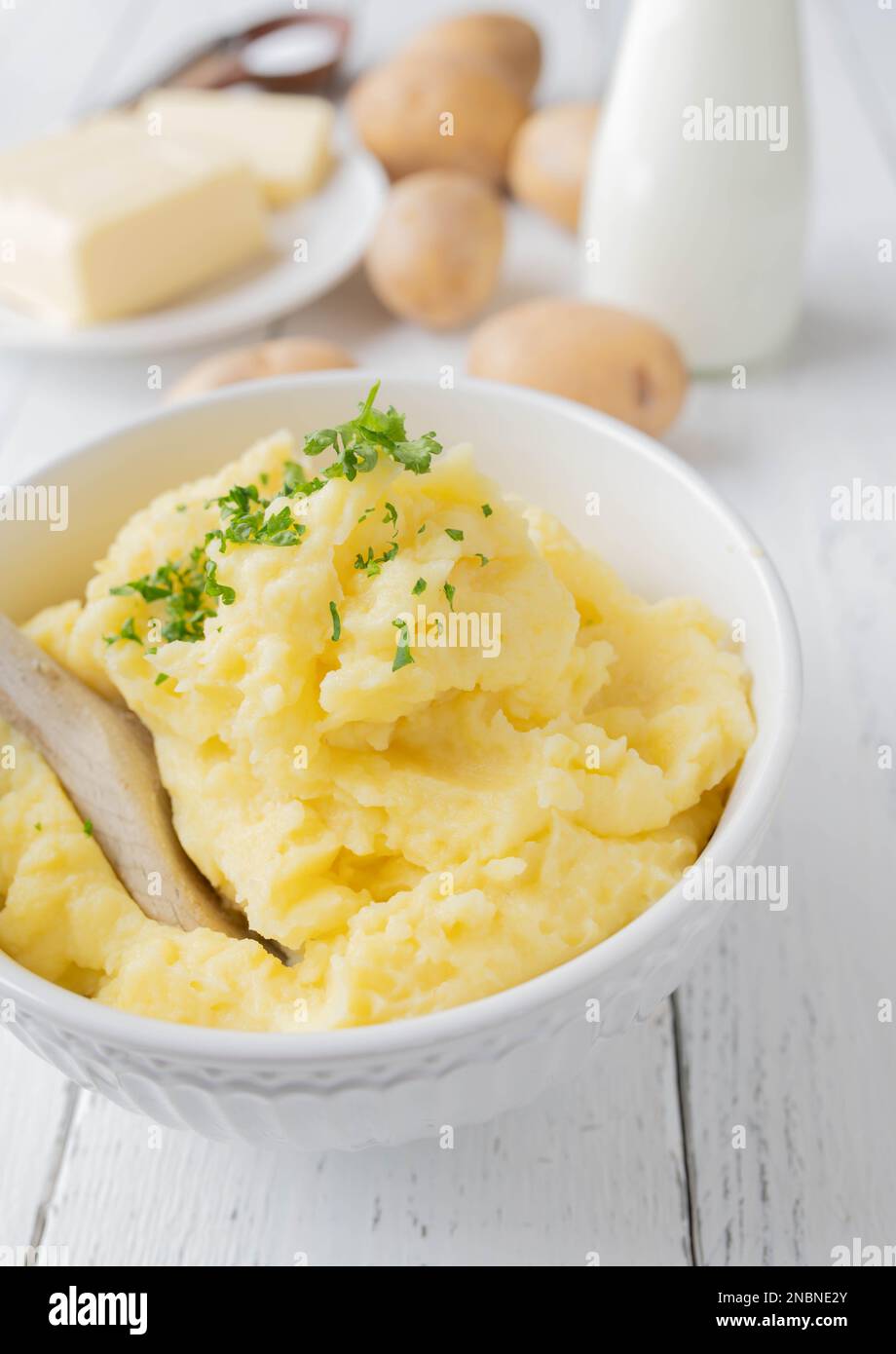 Purè di patate in una ciotola su sfondo bianco con spazio per il testo e ingredienti per la cottura Foto Stock