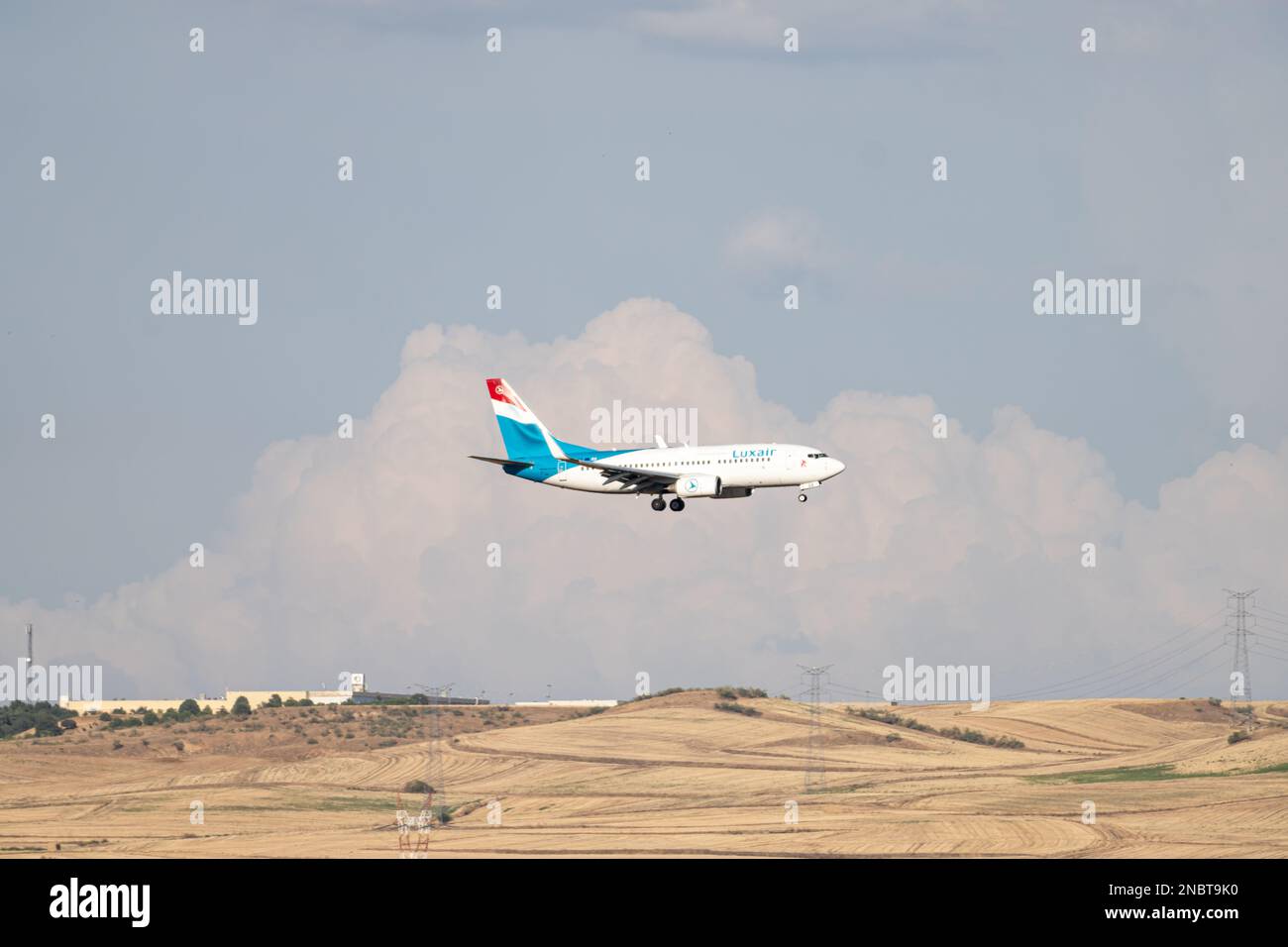 Aereo di linea Luxair bianco, blu e rosso, con il carrello abbassato, in avvicinamento all'aeroporto Barajas di Madrid. Foto Stock