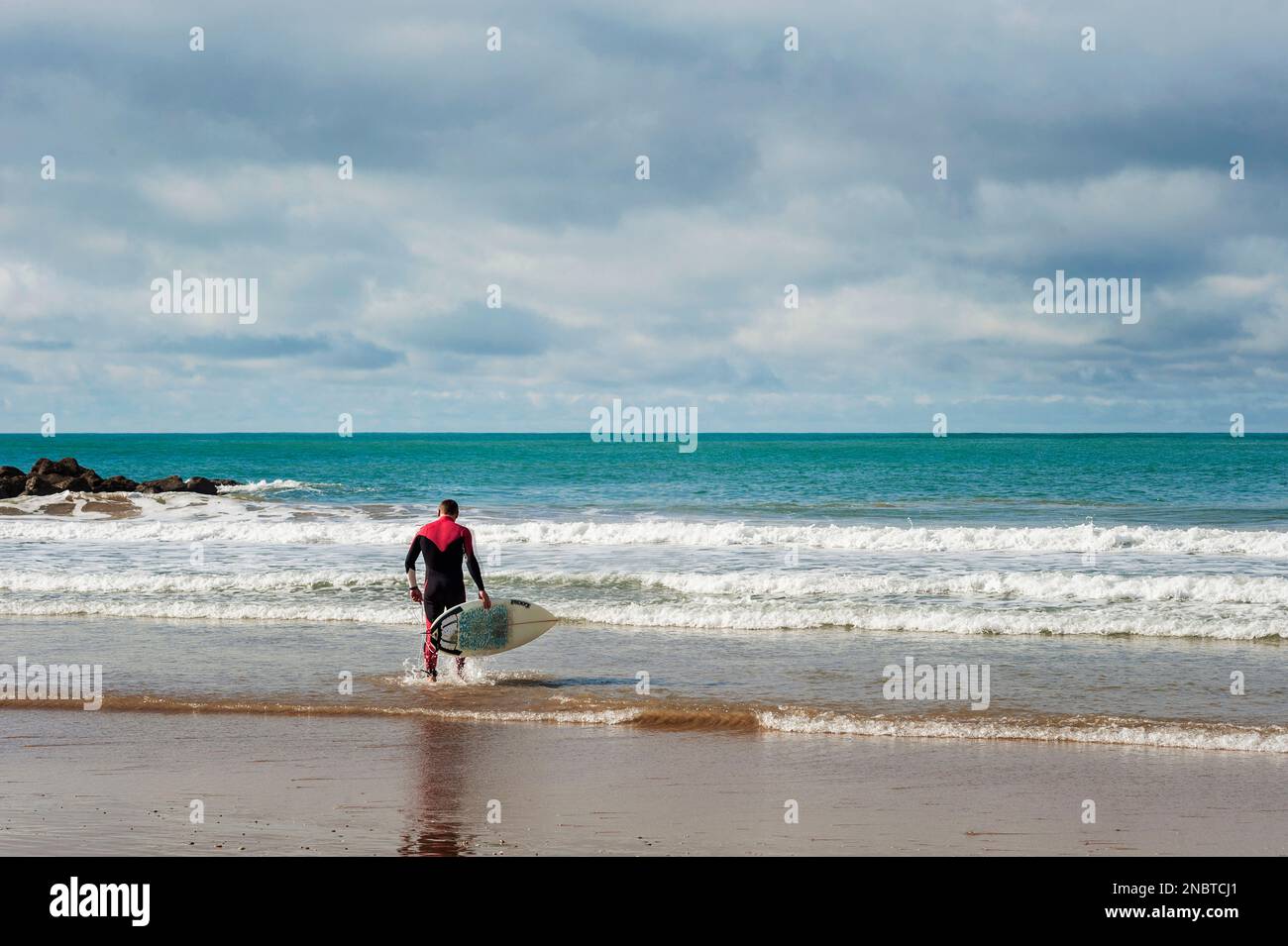 Un uomo va a fare surf a Cadice, Spagna Foto Stock