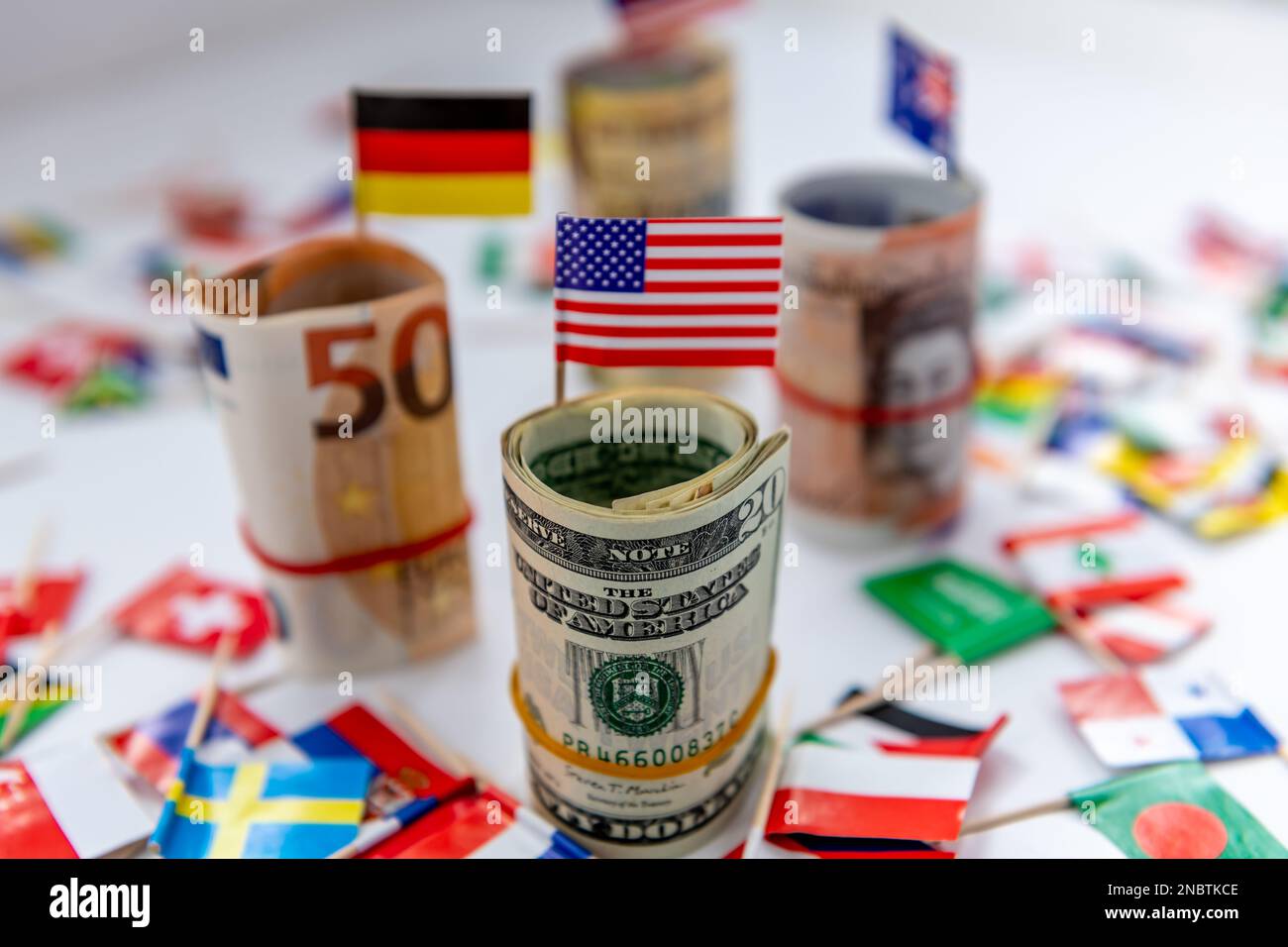 Pacchetti rotolati delle valute principali e bandiere del paese con il dollaro degli Stati Uniti e la bandiera americana davanti. Concetto di egemonia del dollaro. Foto Stock